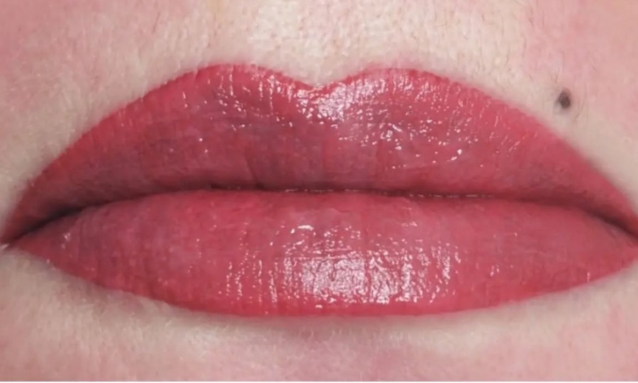 Lèvres rouges redessinées en bouche bisou et grain de beauté permanent au-dessus de la lèvre