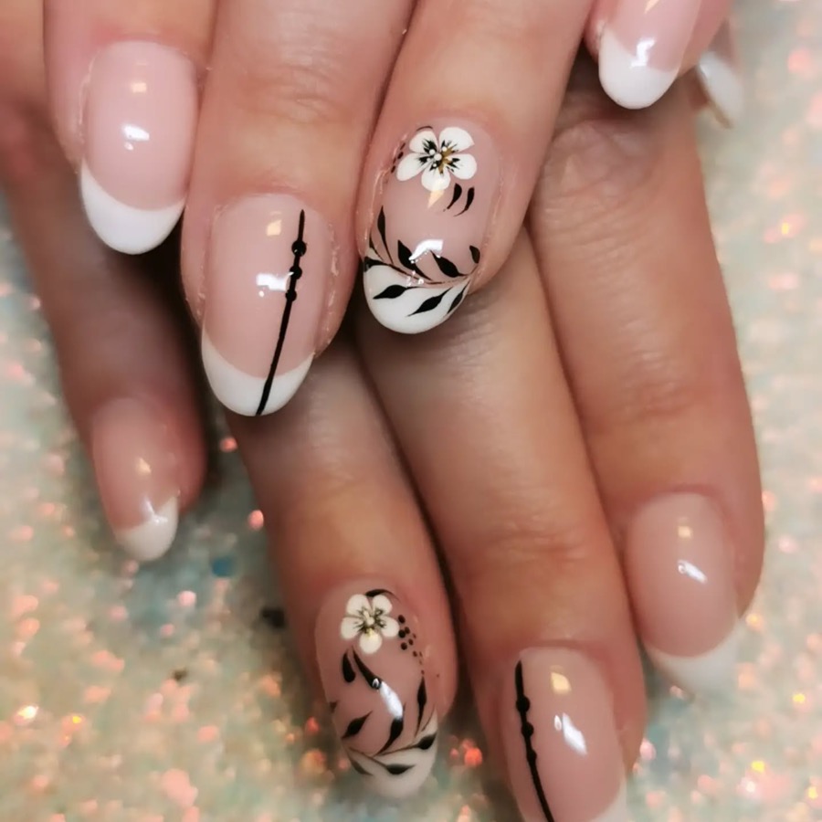 Ongles à french blanche, deux ongles décorés d'une fleur noire et blanche et d'un trait noir