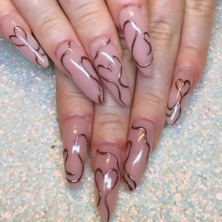 Ongles longs en amande, base nude et arabesques chocolat dessinées